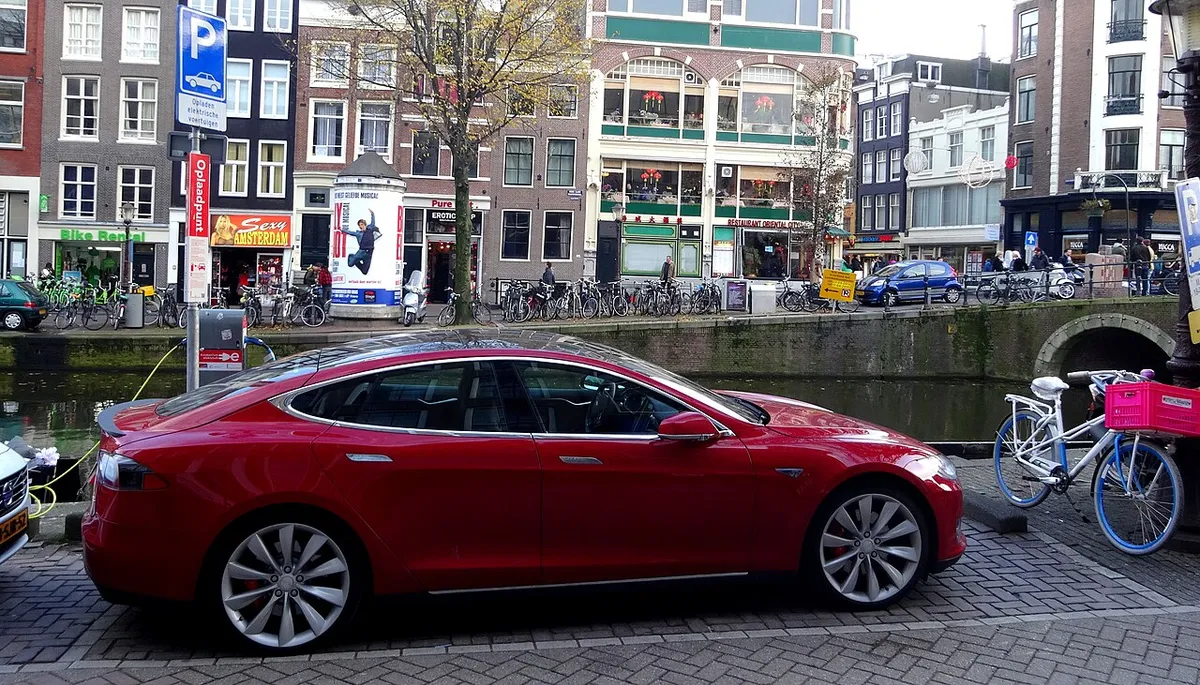 Tesla Model S rojo cargando en un punto de recarga en una calle de Ámsterdam